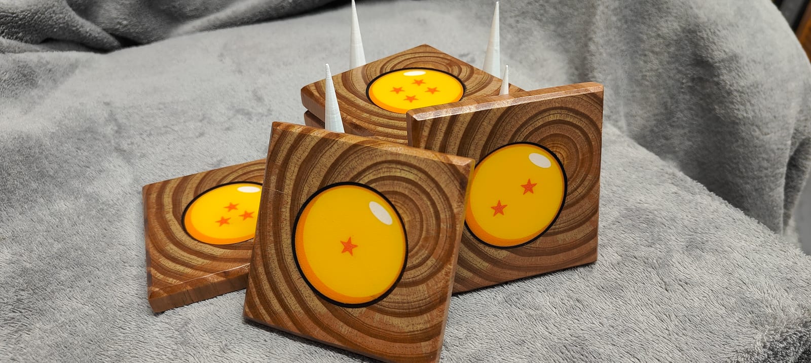 Seven Dragon Ball coasters with orange centers and a black display holder on a tabletop