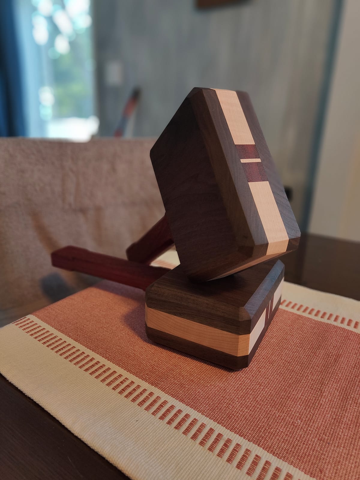 Striped hardwood mallet made from walnut, maple, and padauk standing upright outdoors