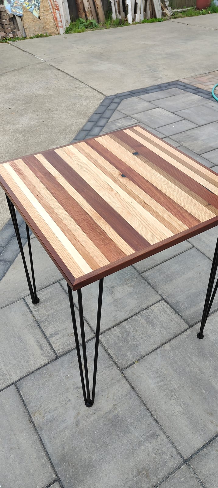 A square striped hardwood side table set against a gray wall