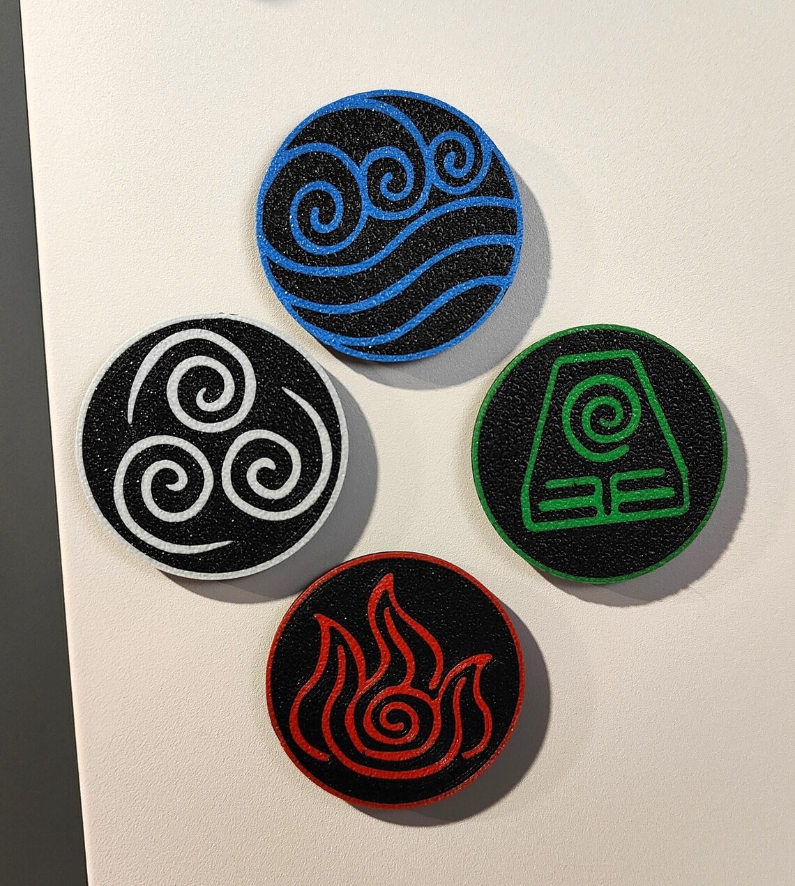 Four colorful 3D-printed elemental magnets arranged on a white surface