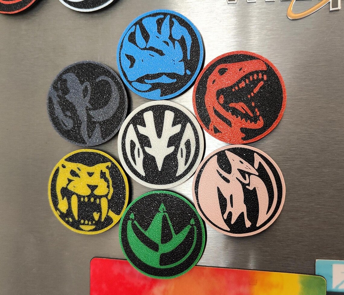 A row of colorful power coin magnets displayed on a white surface